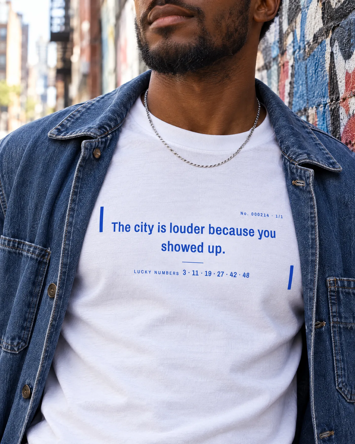 Close-up of the fortune slip print on a white tee, worn under an open denim jacket